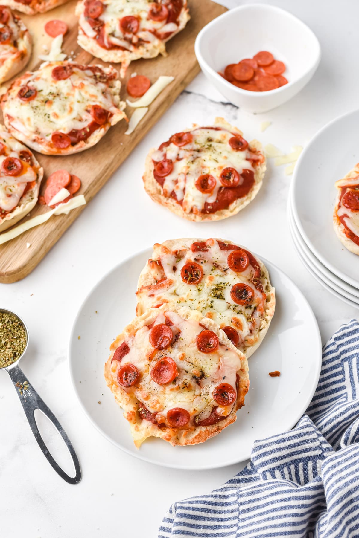 Pieces of Air Fryer English Muffin Pizzas on a white plate with linen on the side
