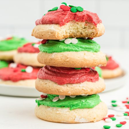 A stack of Christmas lofthouse cookies with green frosting and red sprinkles.