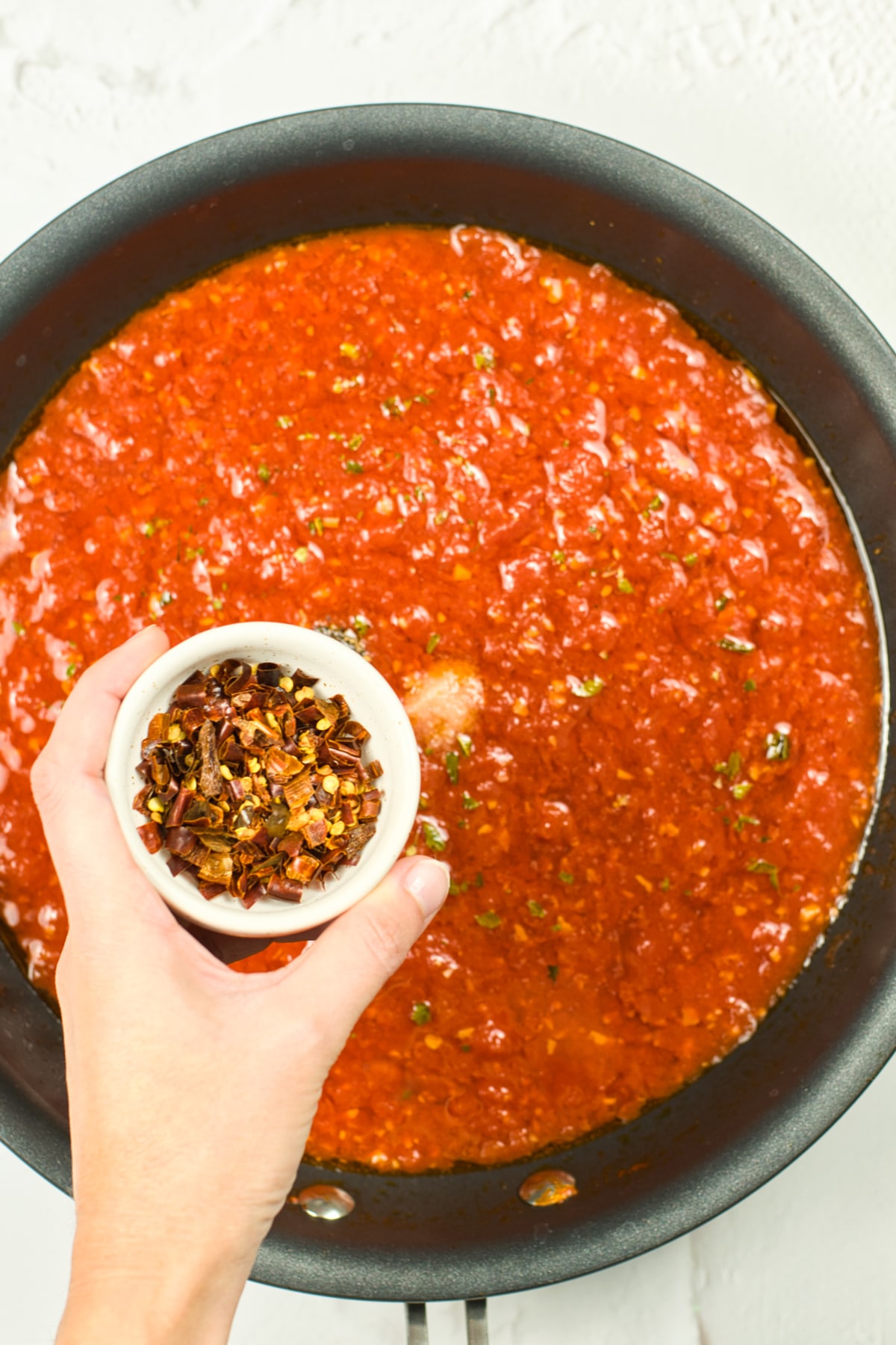 Adding seasoning to Italian Marinara Sauce mixture