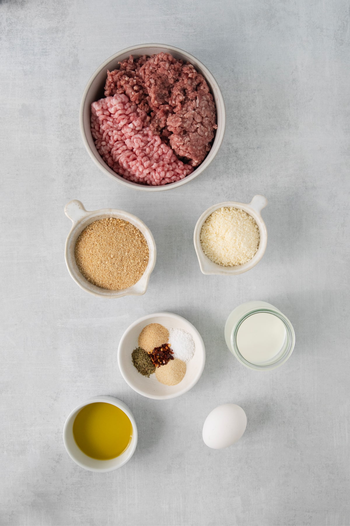 Ingredients for Italian Wedding Soup meatballs include large egg, milk, breadcrumbs, parmesan, onion powder, garlic powder, salt, dried Italian seasoning, red pepper flakes. ground beef, ground pork, and olive oil.