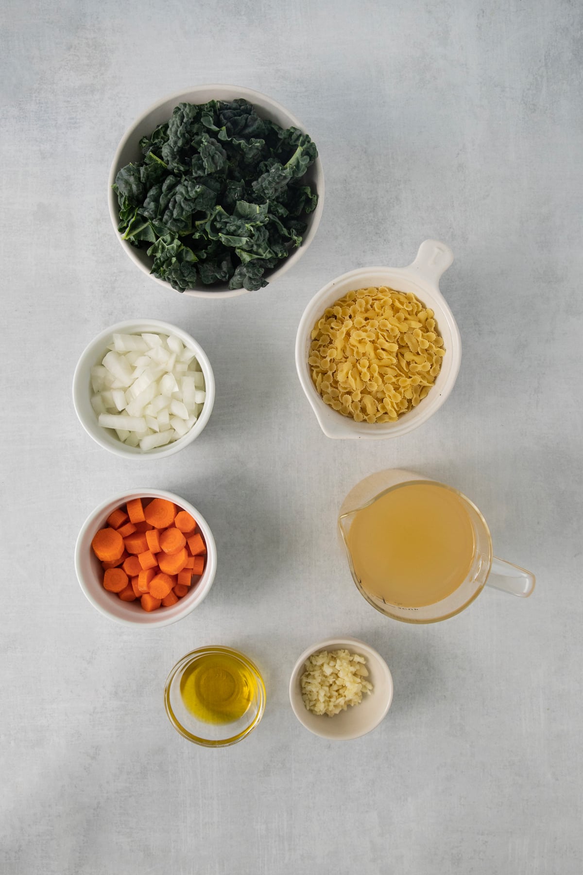 Ingredients for the Italian Wedding Soup are the following: Olive oil, sliced carrots, diced onion, chicken stock, dried pasta, and tuscan kale.