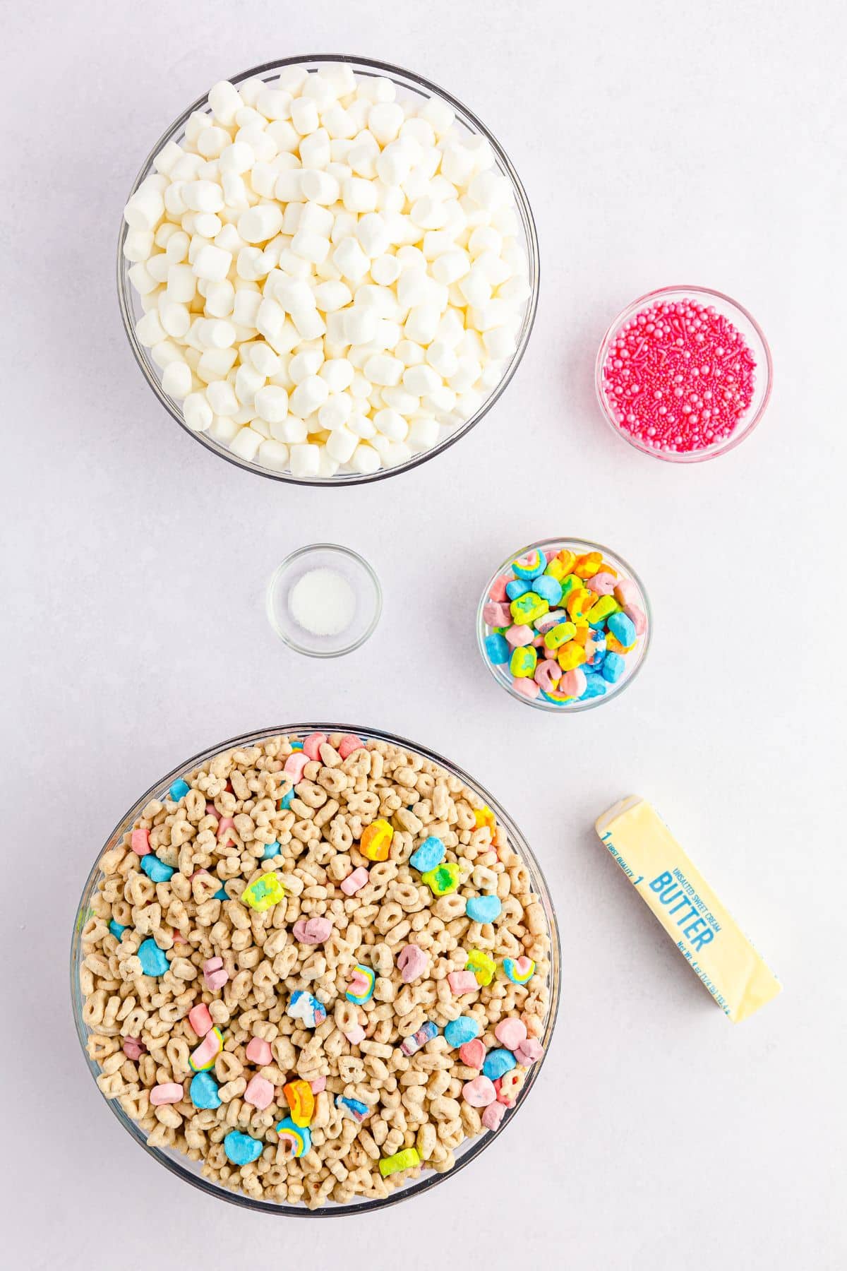 mini marshmallows, Lucky Charms cereal, a stick of butter, and sprinkles on counter
