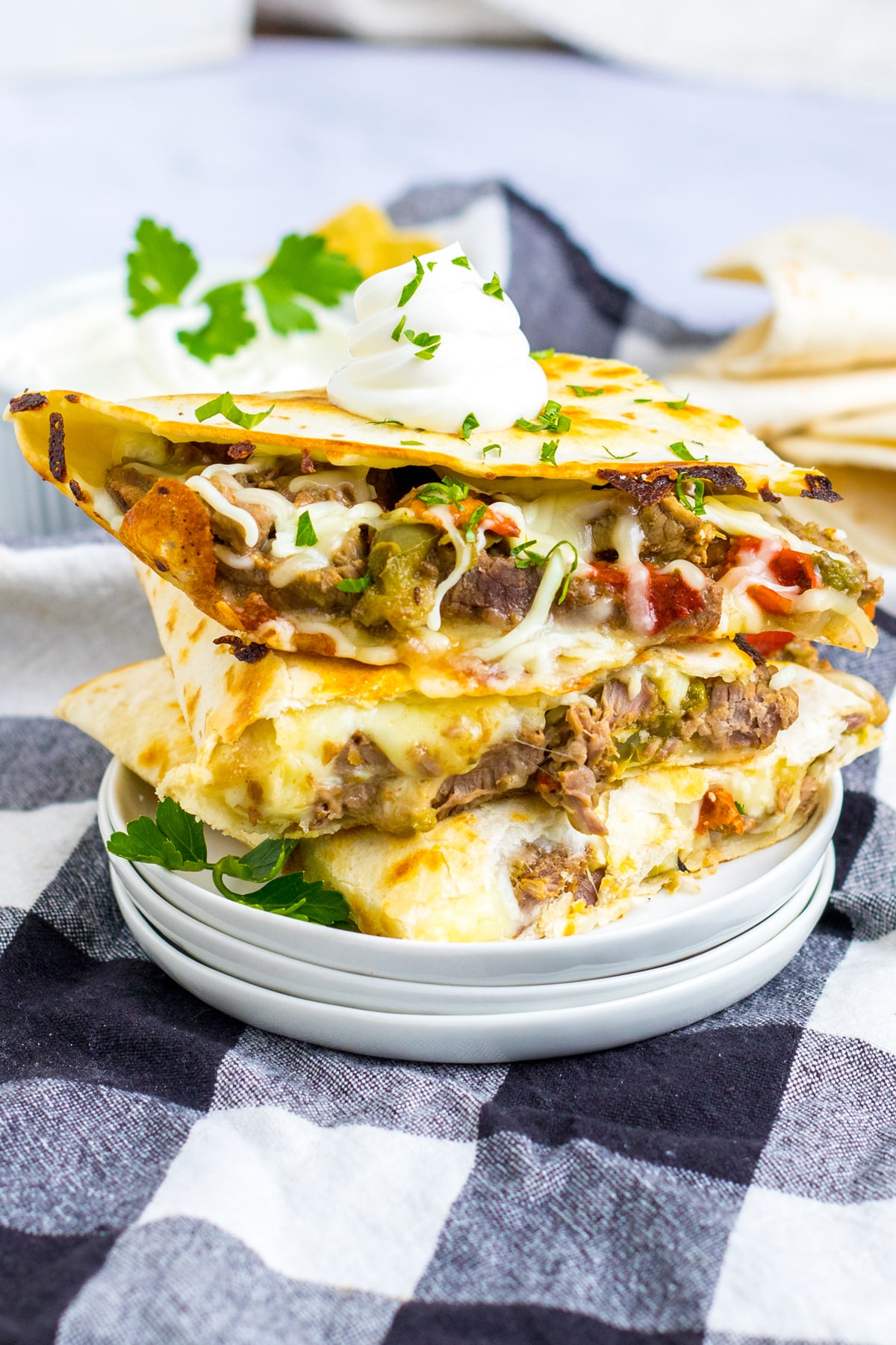 Pieces of Slow Cooker Cheesesteak Quesadillas on a white plate with checkered linen