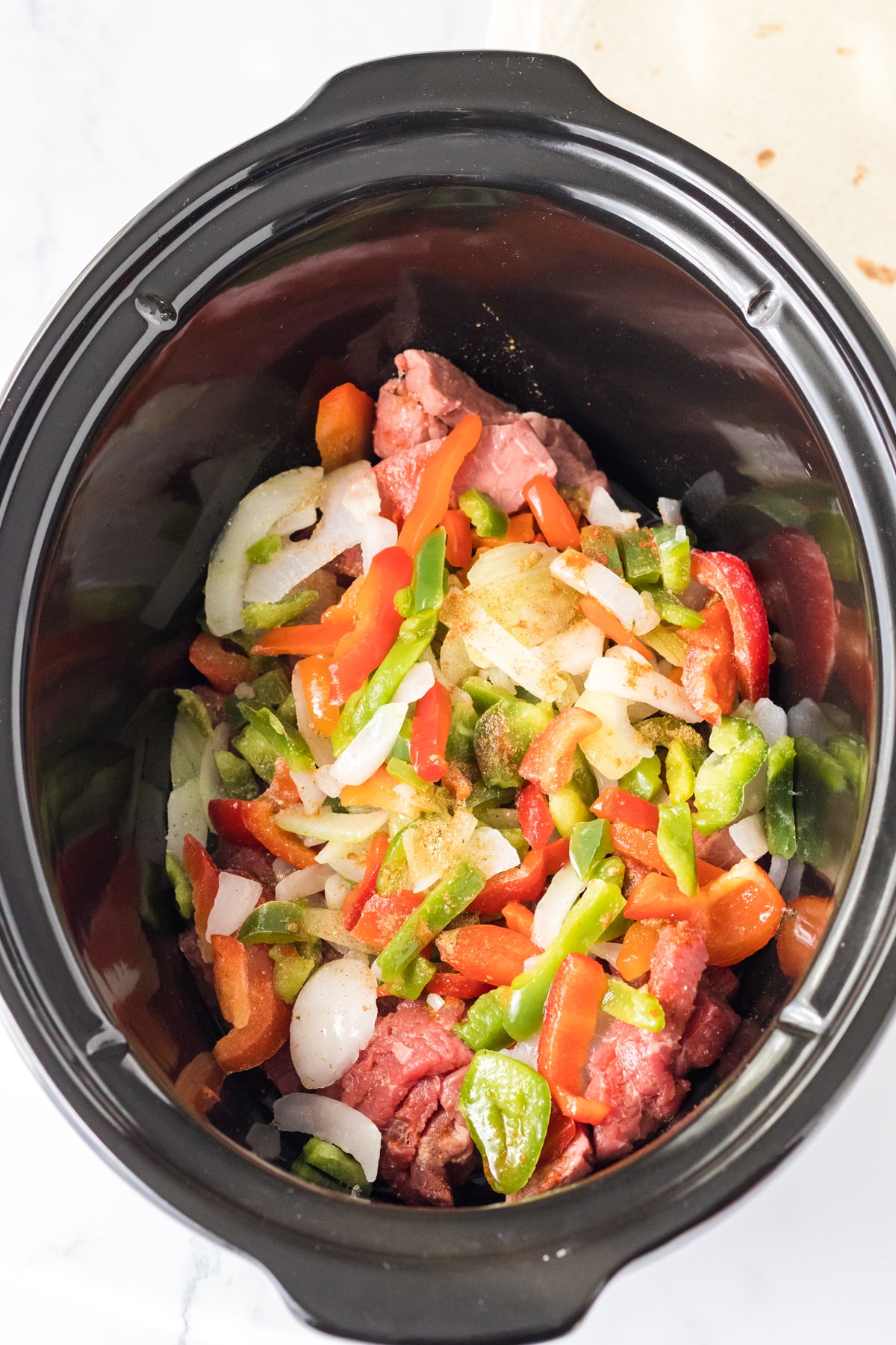 Mixing meat and vegetables for Slow Cooker Cheesesteak Quesadillas recipe