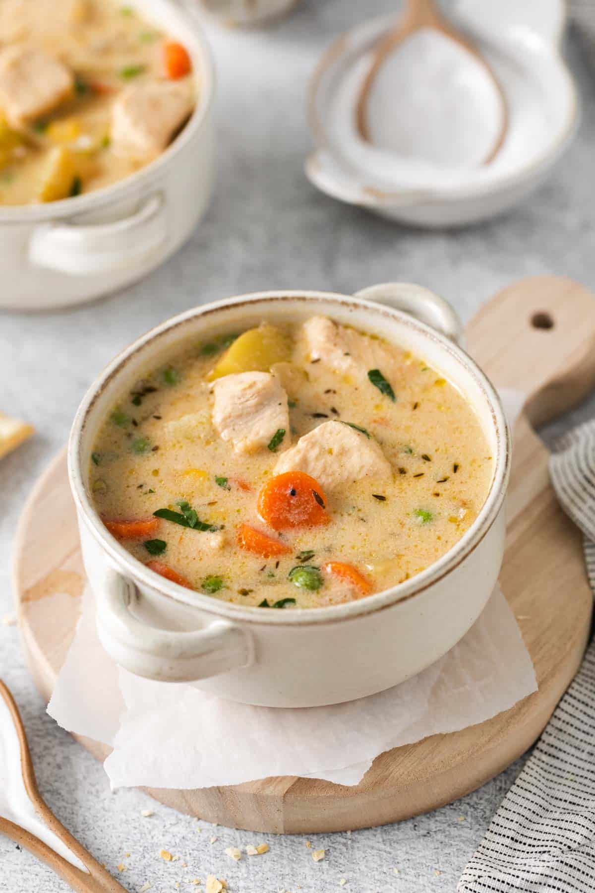 white bowl with chicken pieces at the top of the soup with carrots and vegetables