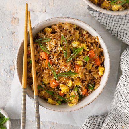 A bowl of Easy Egg Fried Rice with sesame seeds on the side.