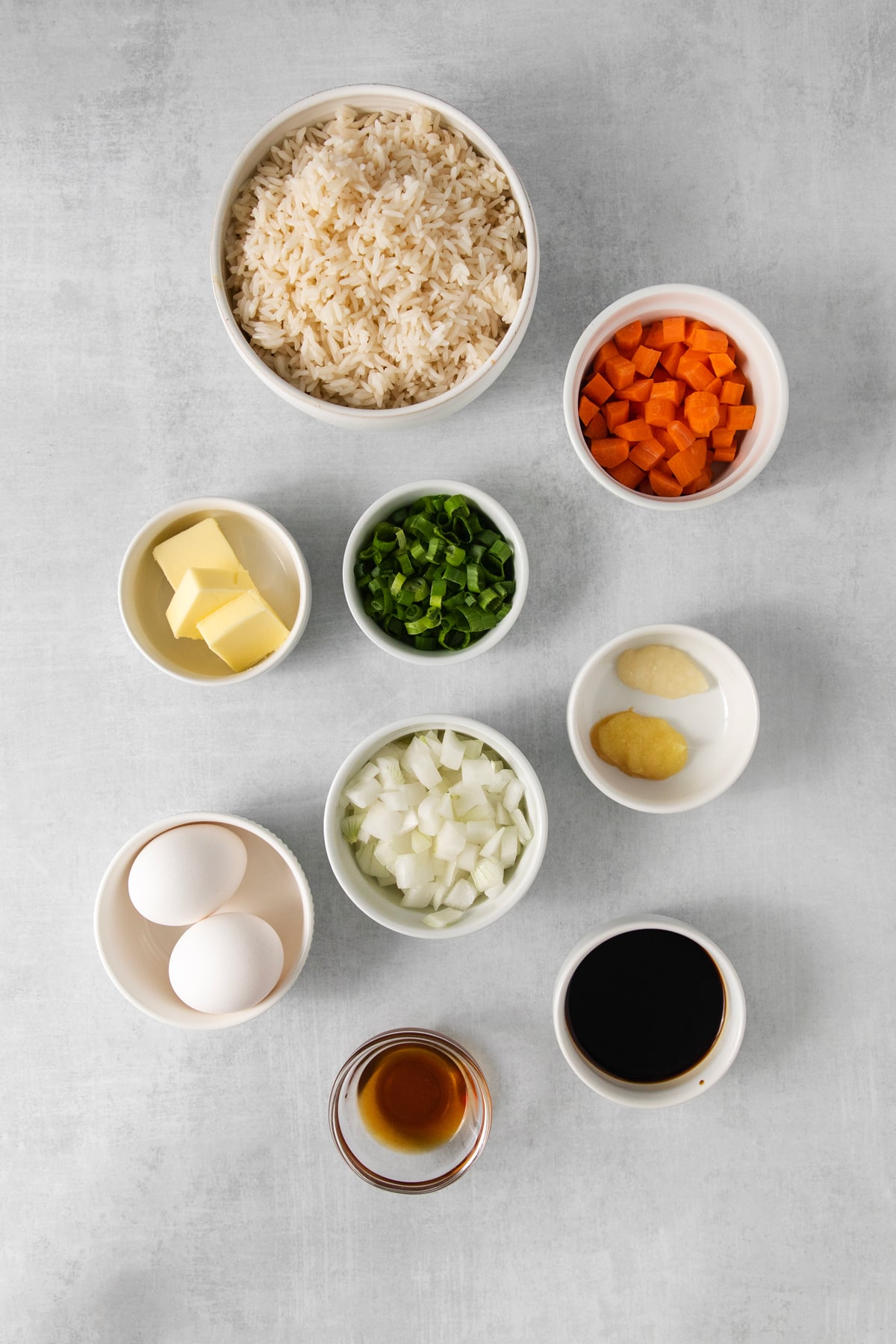 Ingredients for Easy Egg Fried Rice are sesame oil, diced onion, diced carrots, grated garlic, grated ginger, butter, cooked rice, soy sauce, and beaten eggs