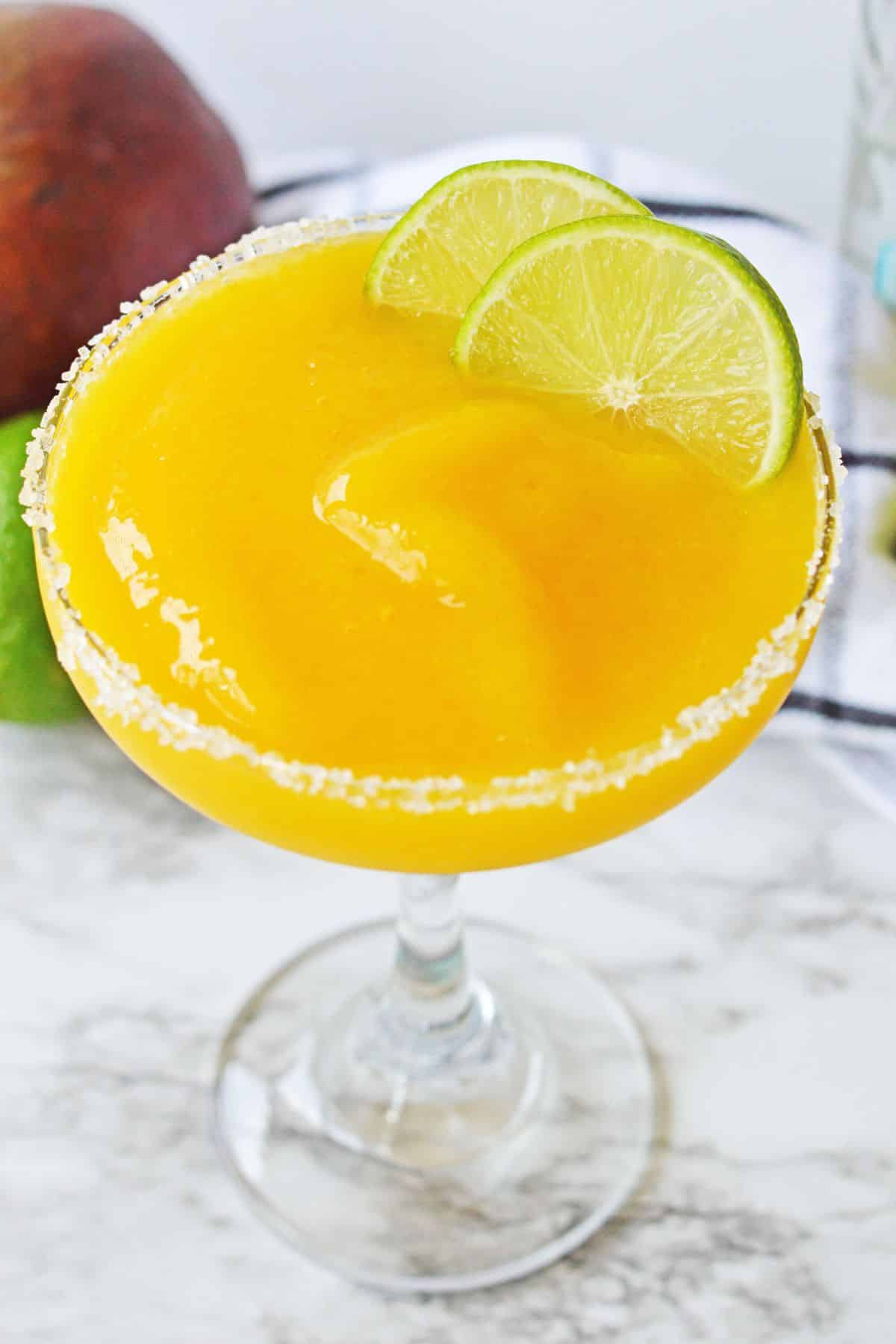 close up of orange mango margarita with salt on the rim of the glass