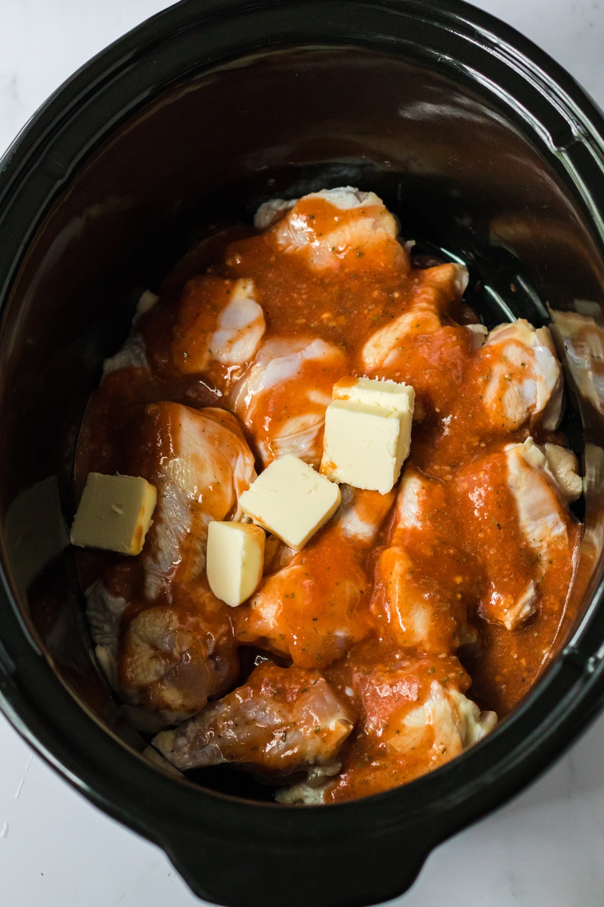 Adding all the ingredients in a slow cooker is one process of preparing Slow Cooker Buffalo Ranch Wings