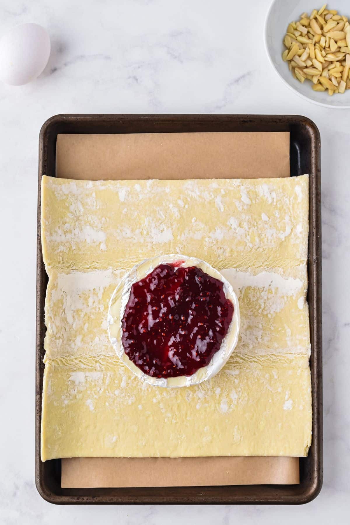 red jelly on top of brie wheel with puffed pastry under