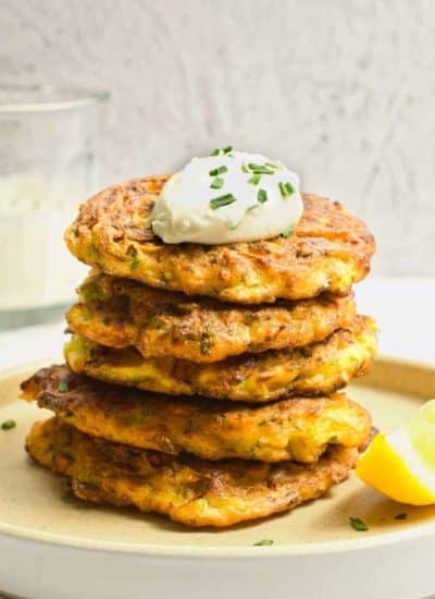 stacked zucchini fritters with sour cream on top