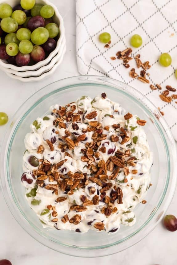 grapes with cream cheese mixture and chopped pecans in clear bowl
