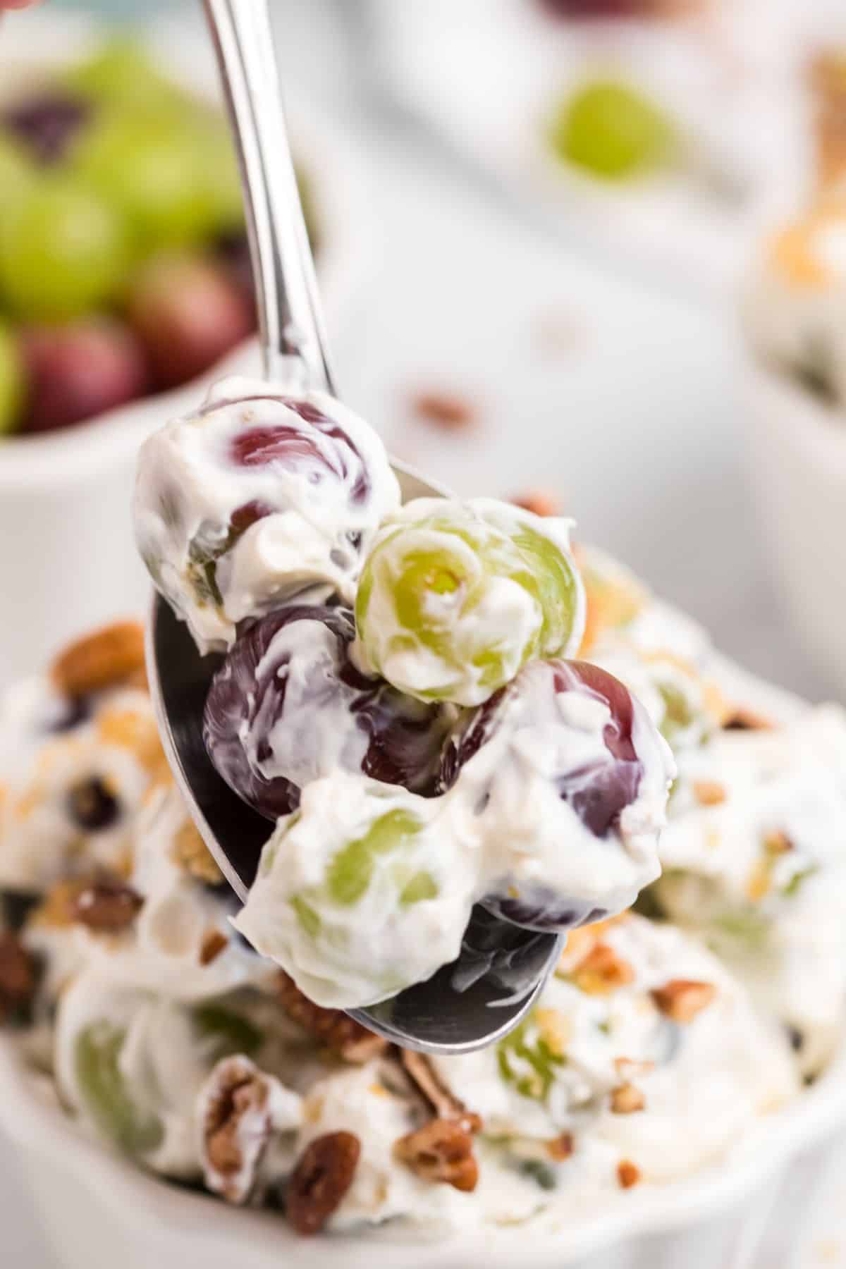 purple and green grapes covered in cream cheese mixture on spoon