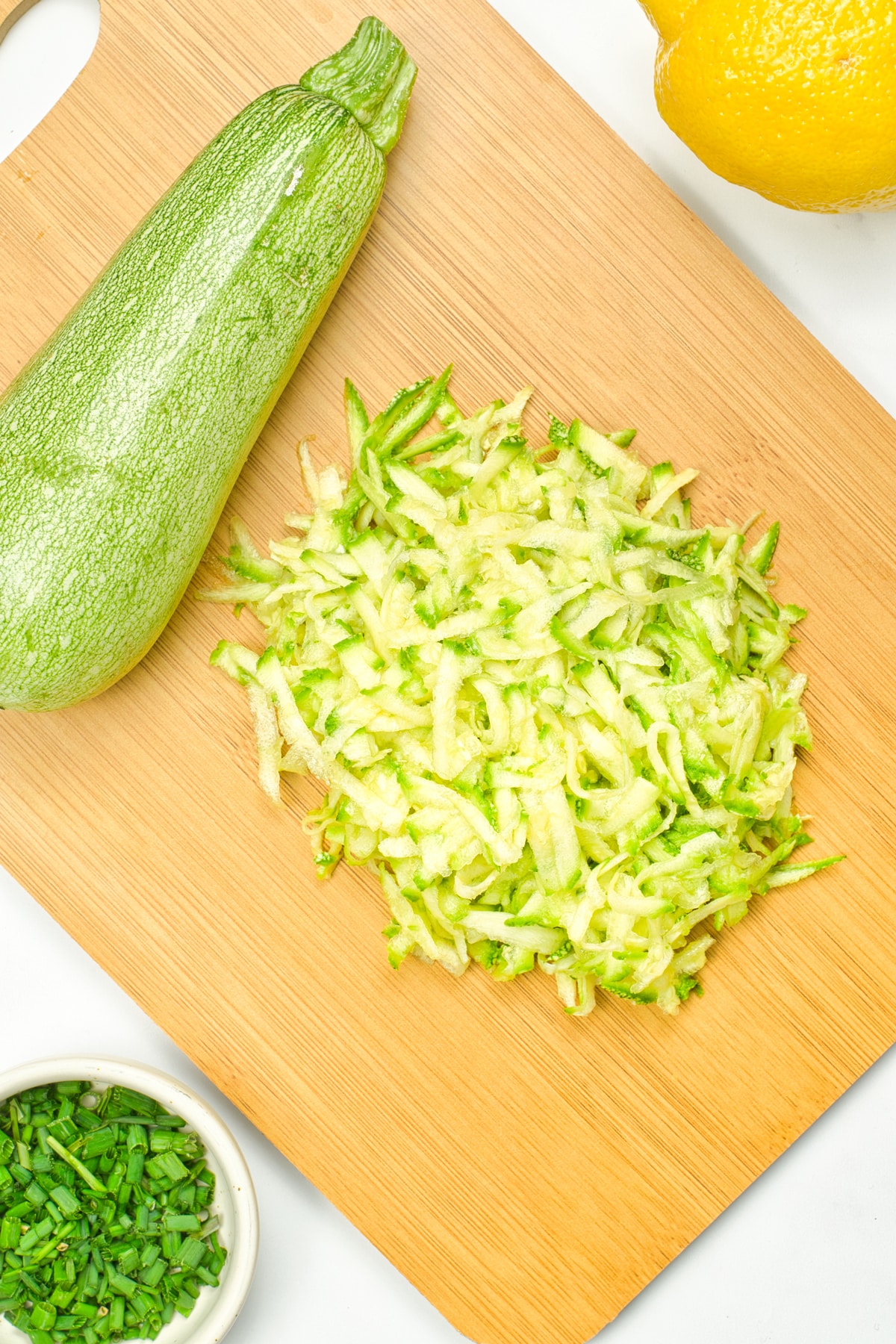 Grated Zucchini on a wooden board for Zucchini Fritters recipe
