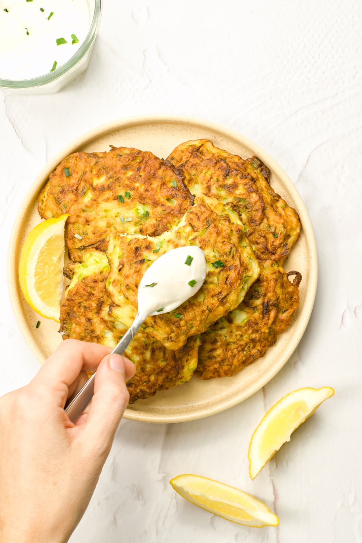 Adding sour cream to a serving of Zucchini Fritters