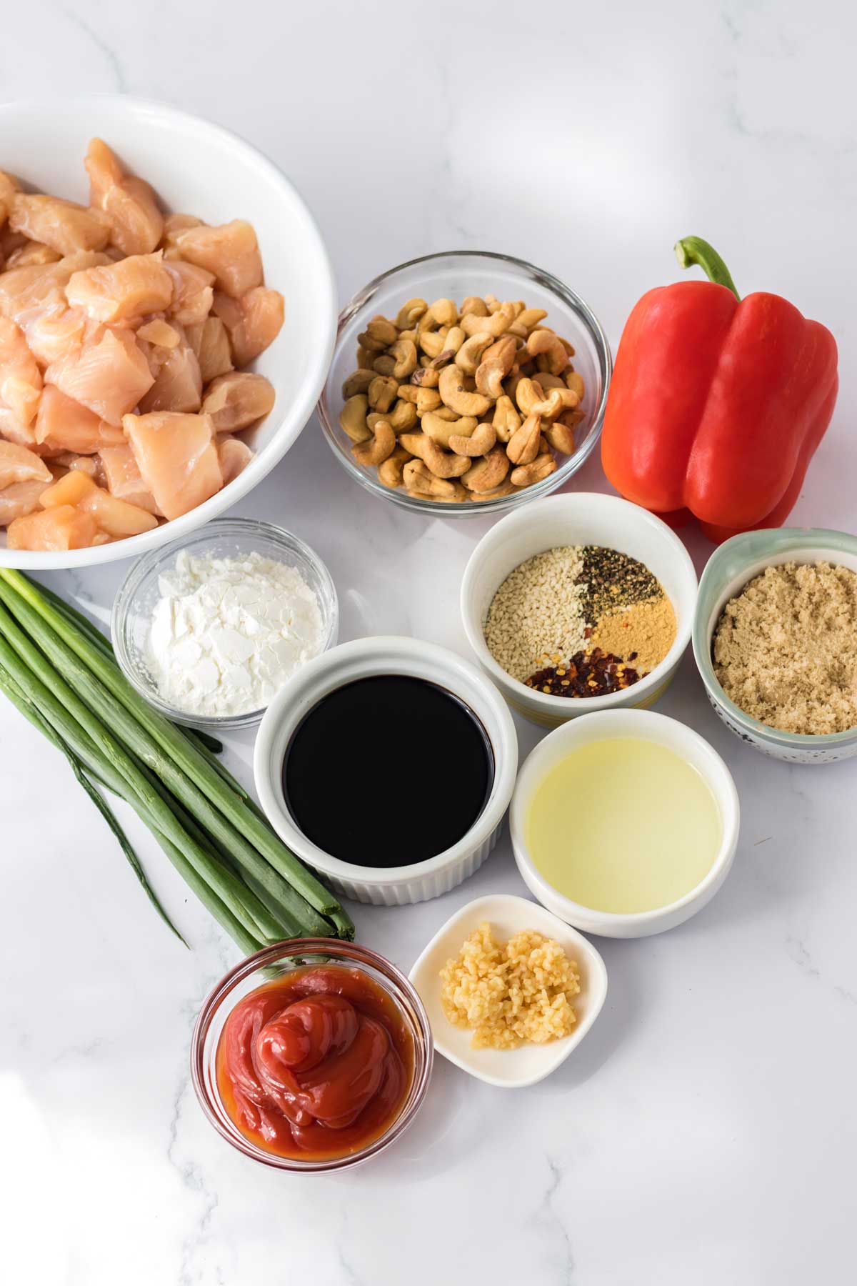 Ingredients for Crockpot Cashew Chicken include Chicken tenderloins, Cornstarch, Vegetable oil, Red bell pepper, Soy sauce (or coconut aminos), Ketchup, Brown sugar, Fresh garlic, Black pepper, Ground ginger, Red pepper flakes (optional), Sesame seeds, Cashews, Scallions (green onions)Chicken tenderloins, Cornstarch, Vegetable oil, Red bell pepper, Soy sauce (or coconut aminos), Ketchup, Brown sugar, Fresh garlic, Black pepper, Ground ginger, Red pepper flakes (optional), Sesame seeds, Cashews and Scallions (green onions)