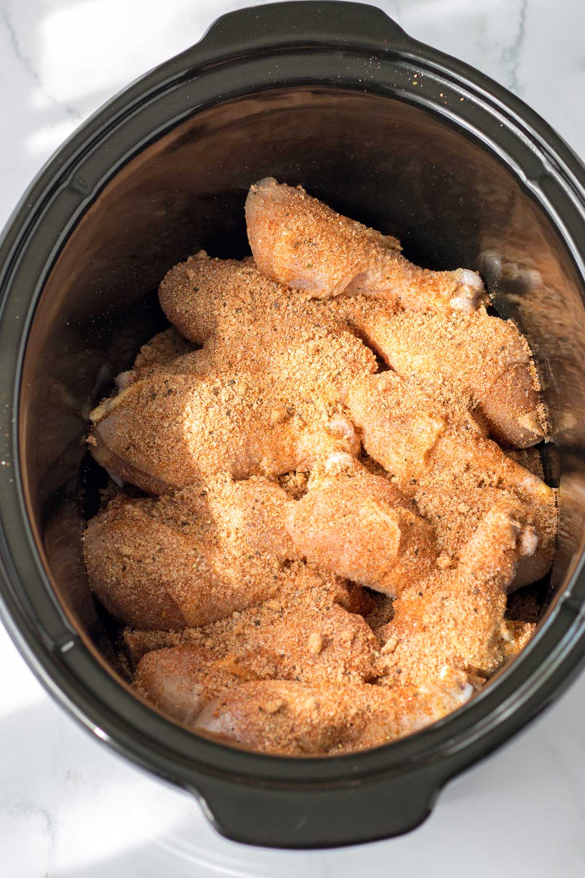 First process in preparing Crockpot BBQ Drumsticks is to add the seasoning mix to the chicken.