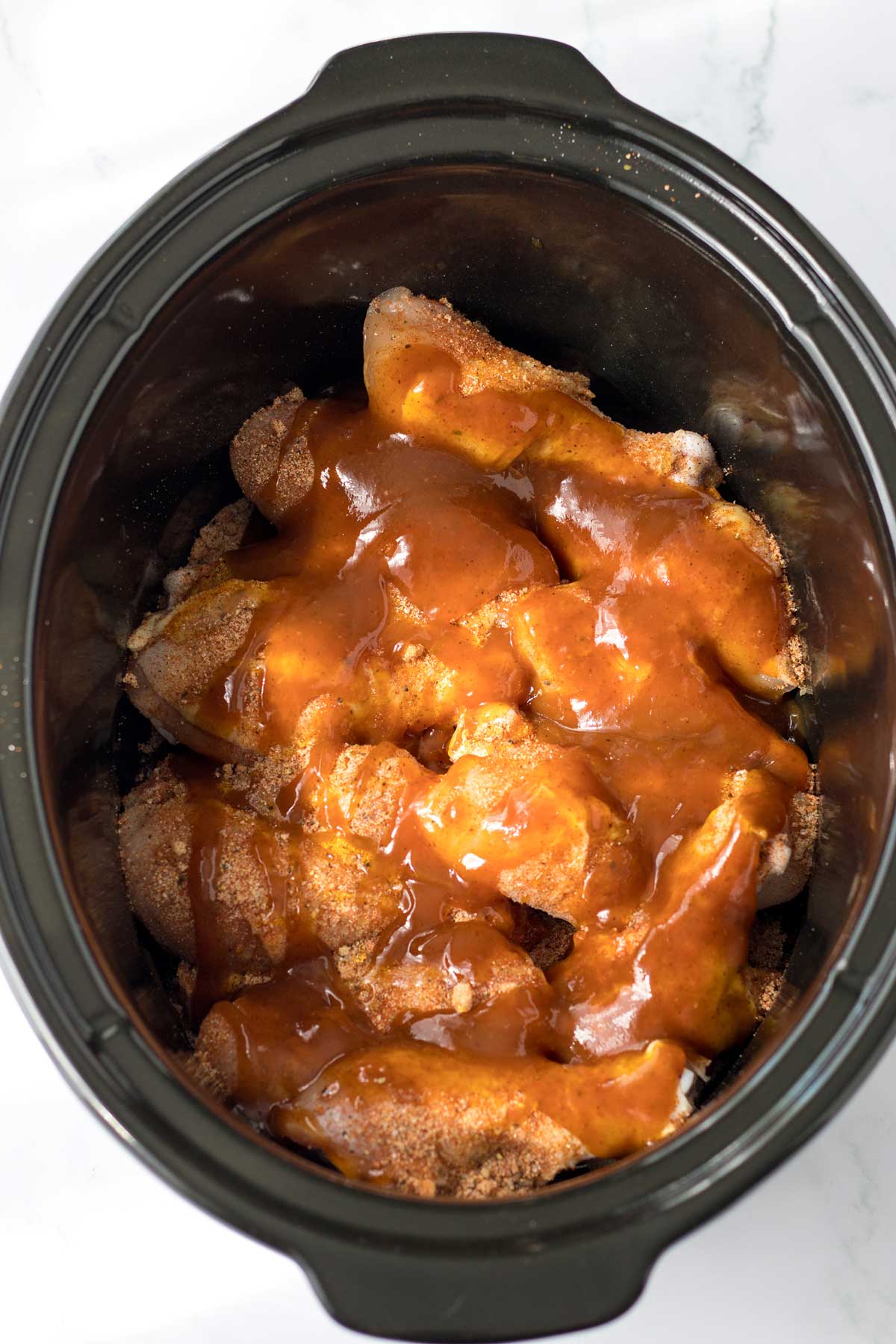 Next process in preparing Crockpot BBQ Drumsticks is to add BBQ sauce and honey to the chicken