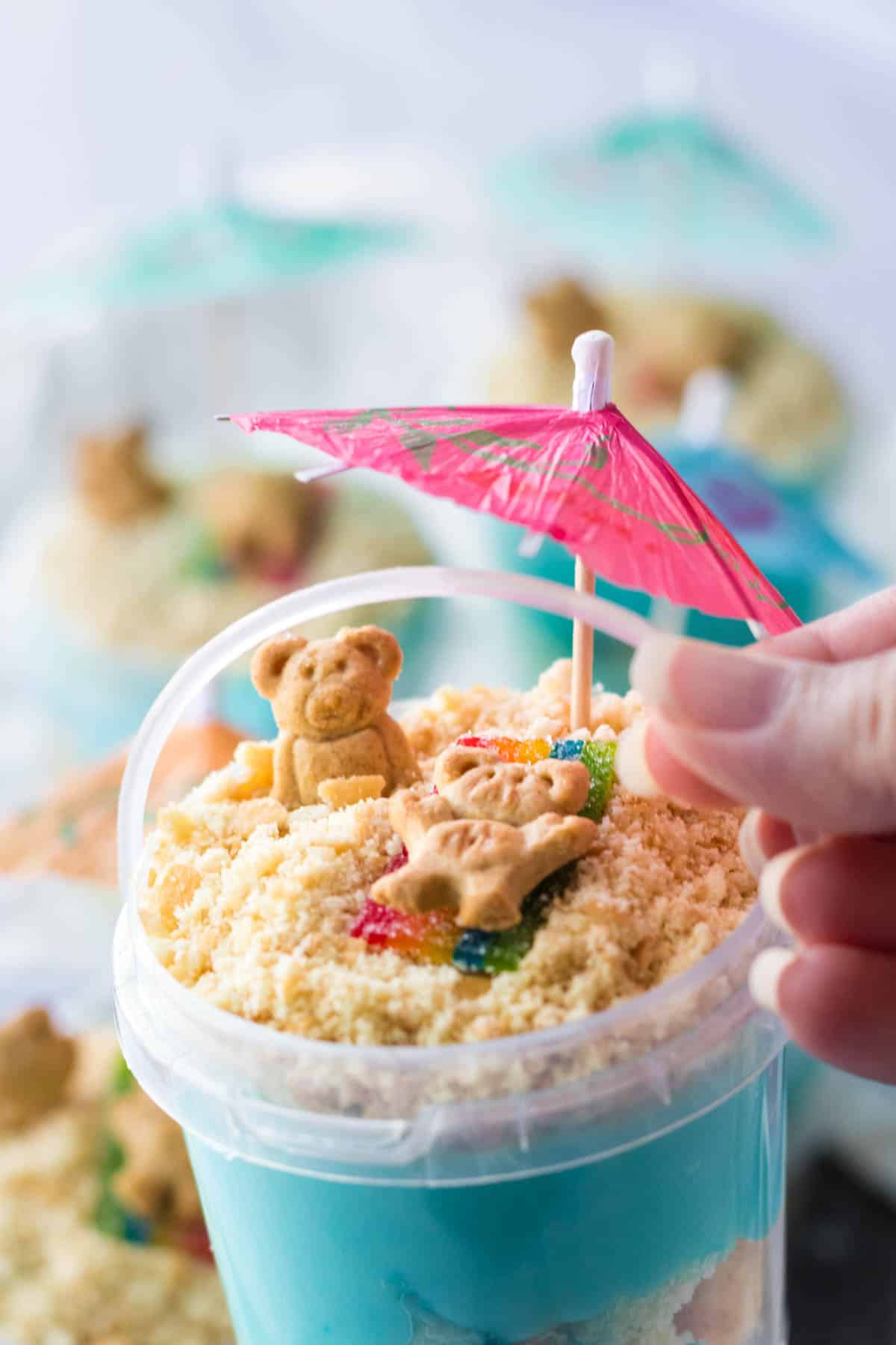 pink umbrella in sand with graham cracker teddy bears