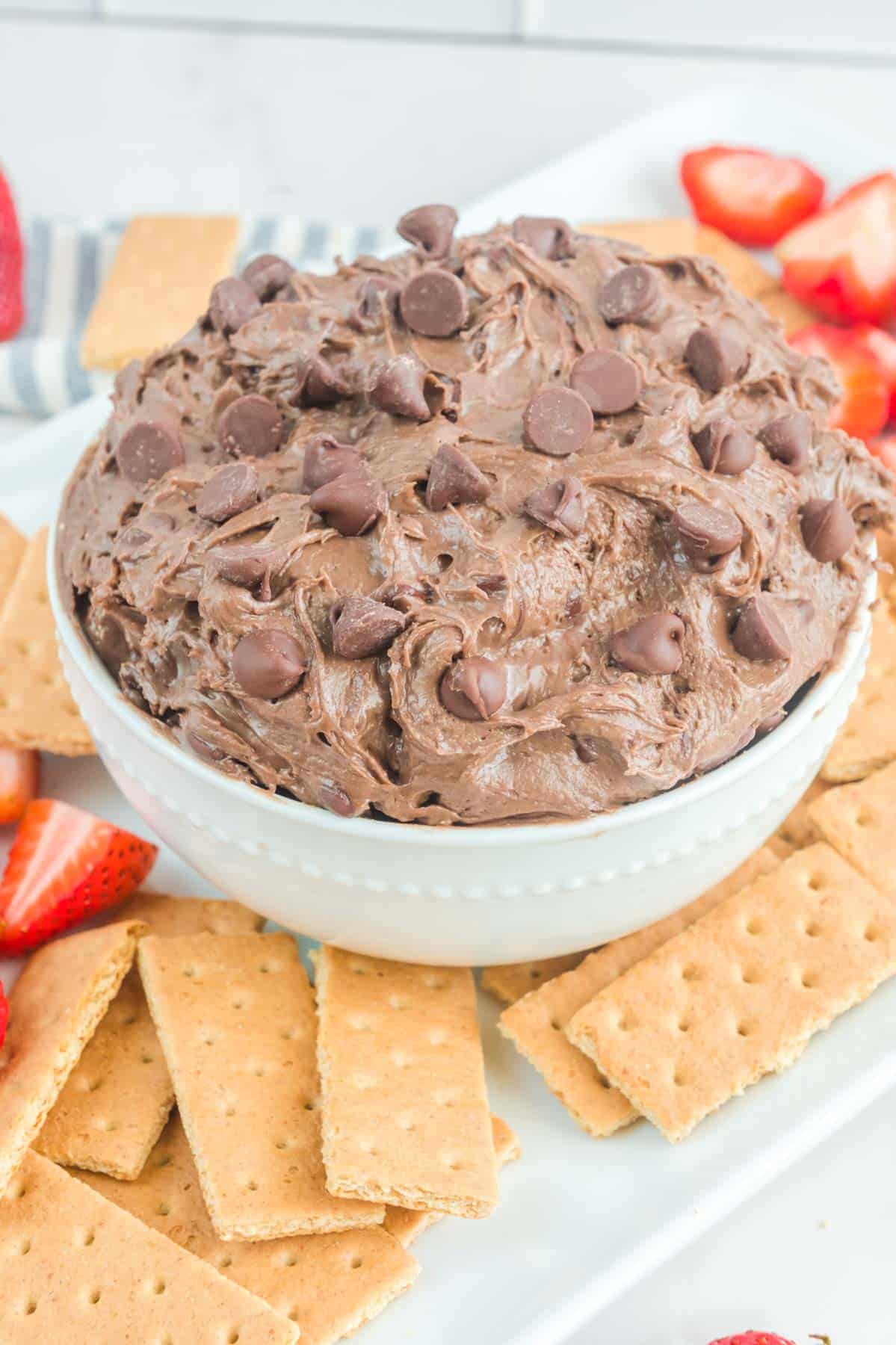 chocolate dip with chocolate chips in bowl with graham crackers and strawberries on the side
