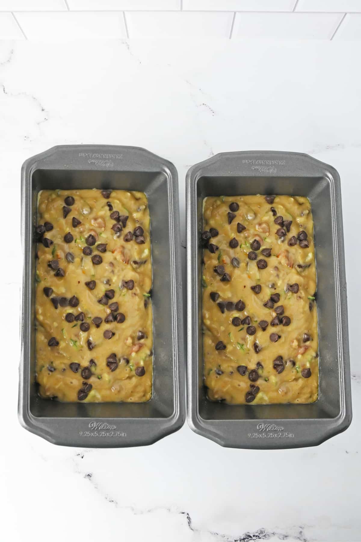 two pans with zucchini bread batter with chocolate chips on top