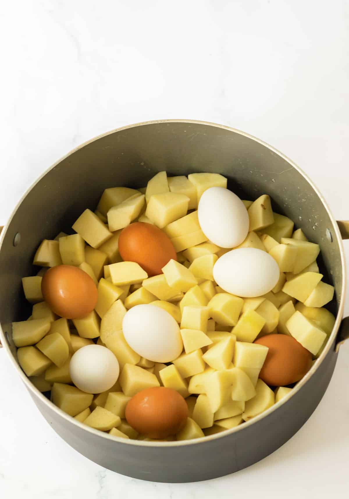 stock pot with diced potatoes and eggs on top