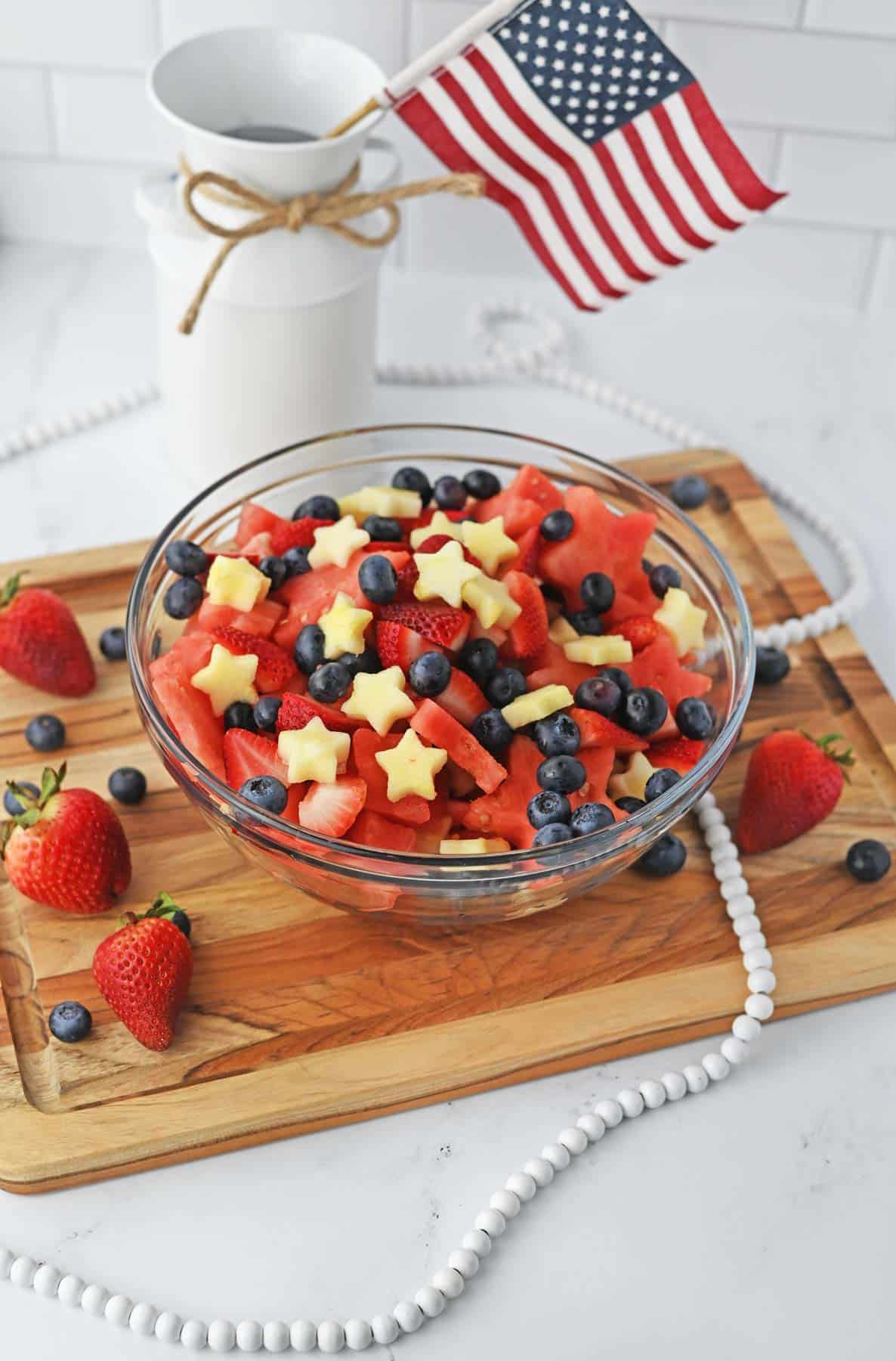 star-shaped fruit with strawberries and blueberries in bowl with small USA flag in background