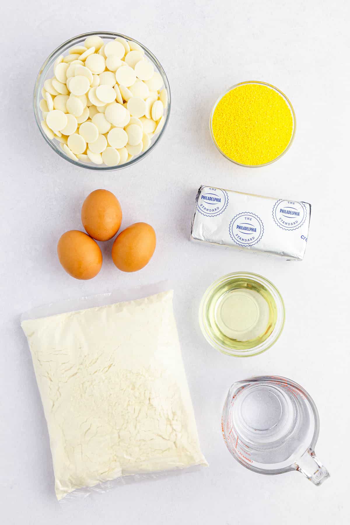 white candy melts, yellow sprinkles, cream cheese, oil, water, 3 eggs, cake mix on counter