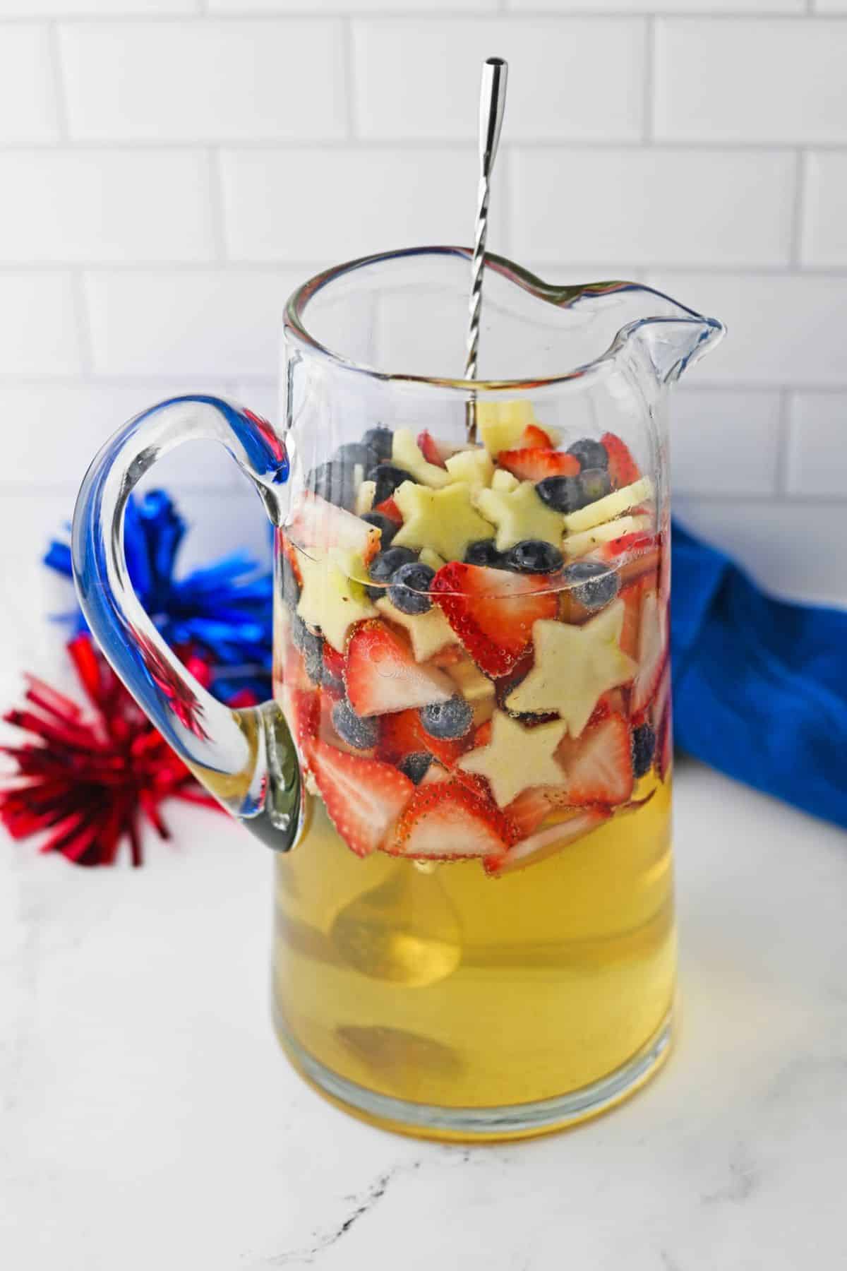 large glass pitcher with white sandria topped with red white and blue fruit