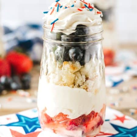 thin mason jar with red white and blue cake and whipped cream parfait with star napkin