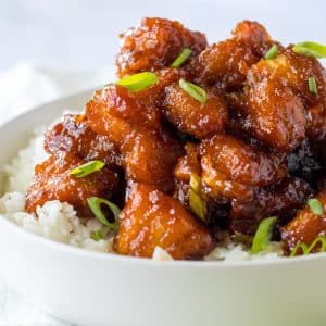 glazed chicken pieces with scallions on white rice