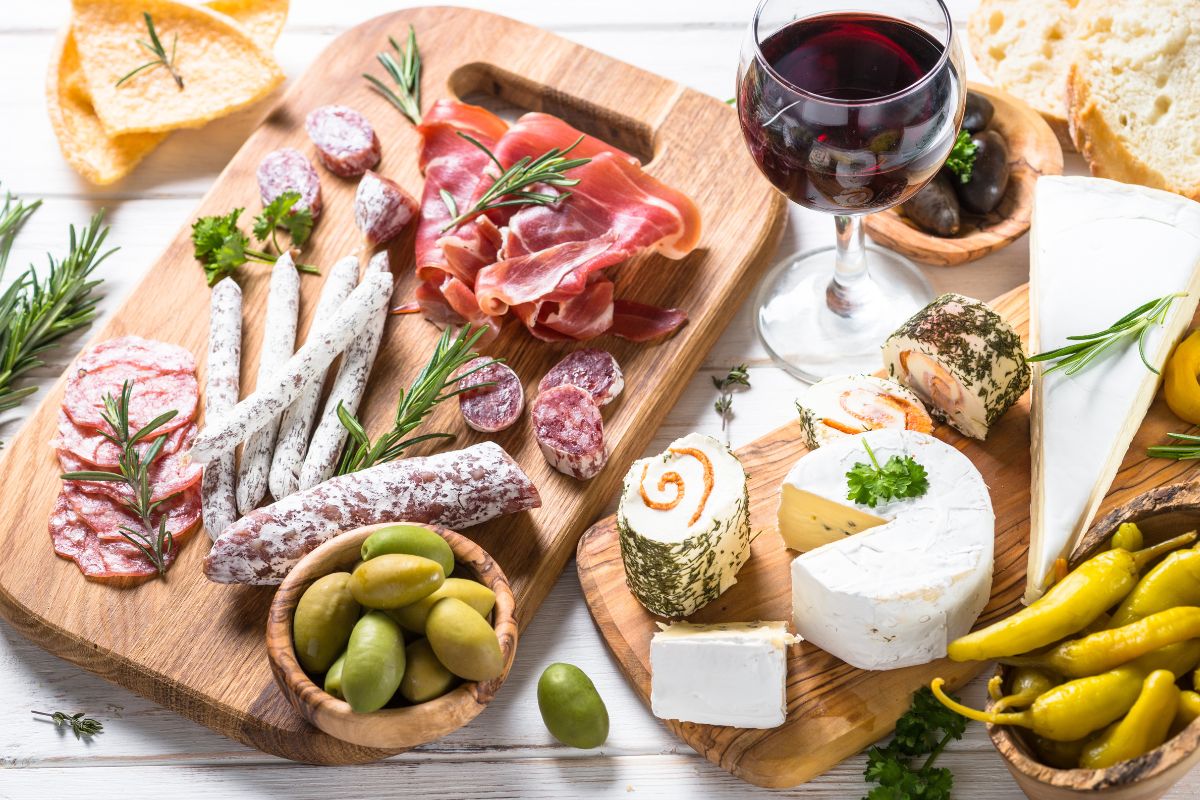 sliced meats, cheeses, and olives with a glass of red wine