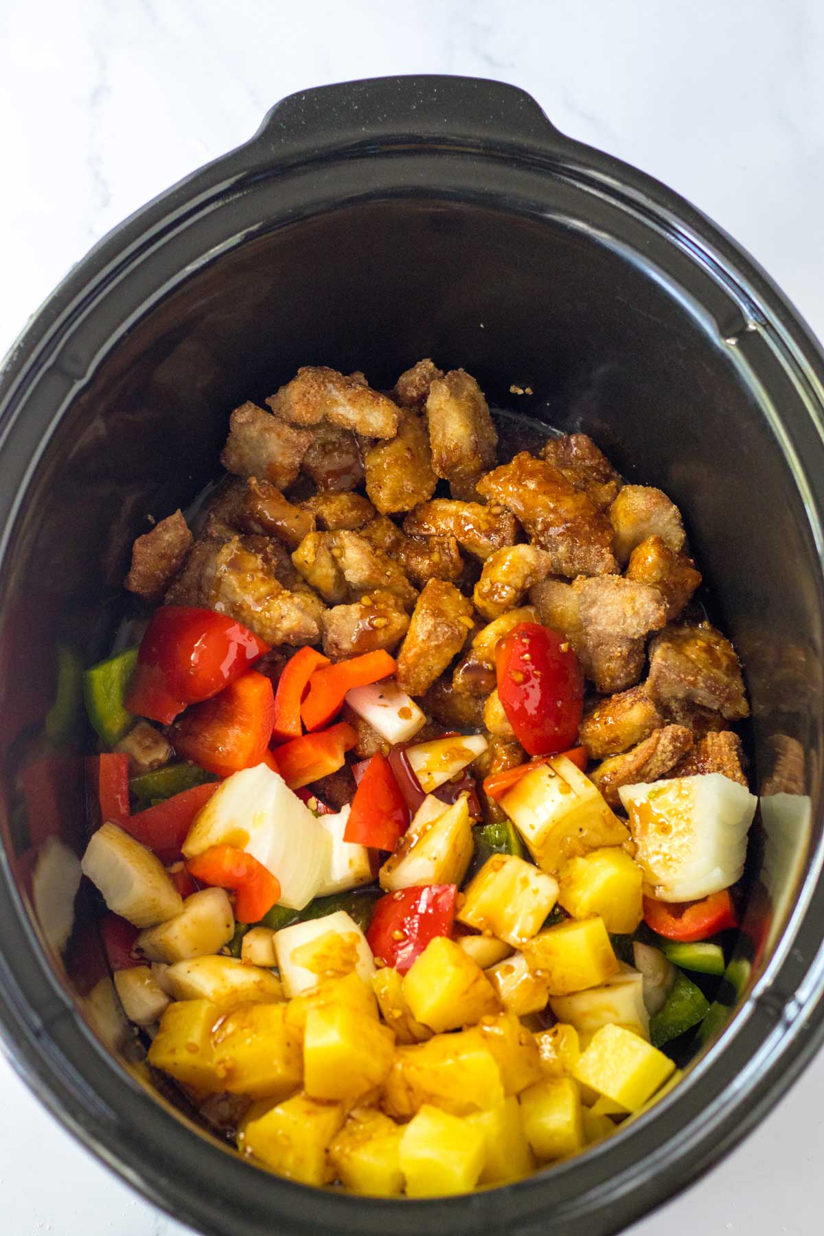 Adding the veggies and pork to the crockpot is a part of Slow Cooker Sweet and Sour Pork