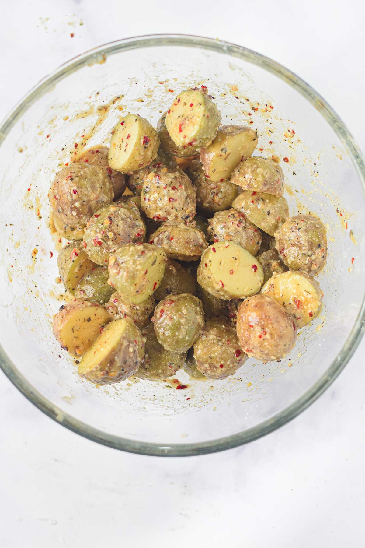 Coating the Air Fryer Parmesan Potatoes with spices in a bowl