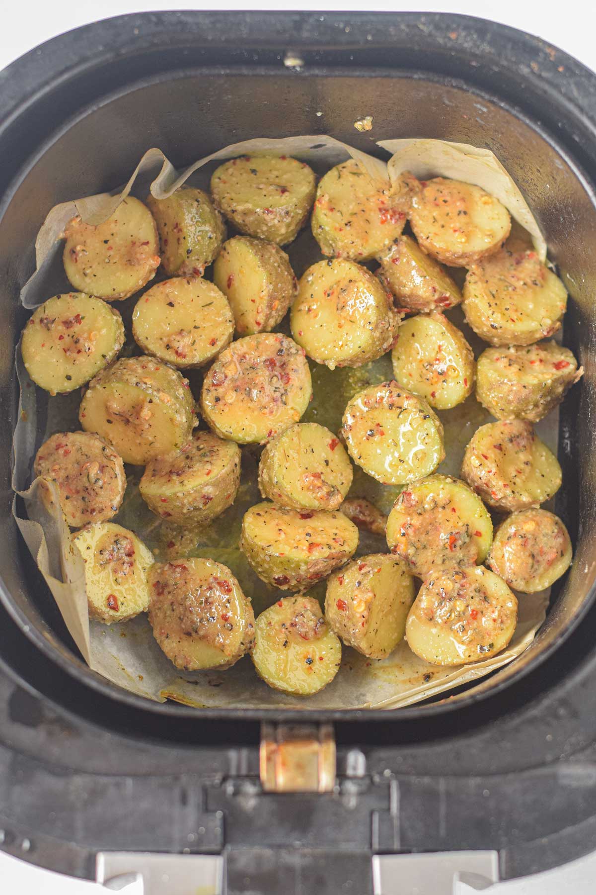 Putting the coated Air Fryer Parmesan Potatoes in an air fryer