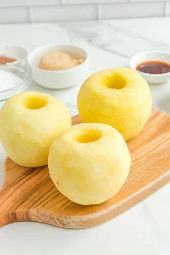 three peeled and cored apples on cutting board