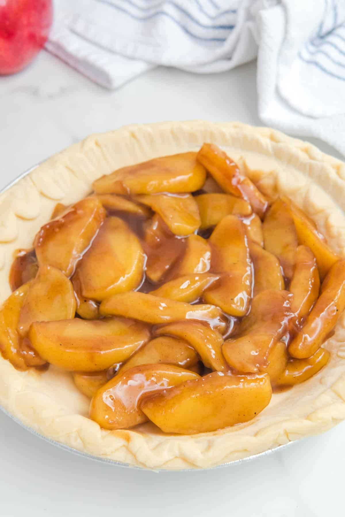 glazed apple pie filling in uncooked pie crust