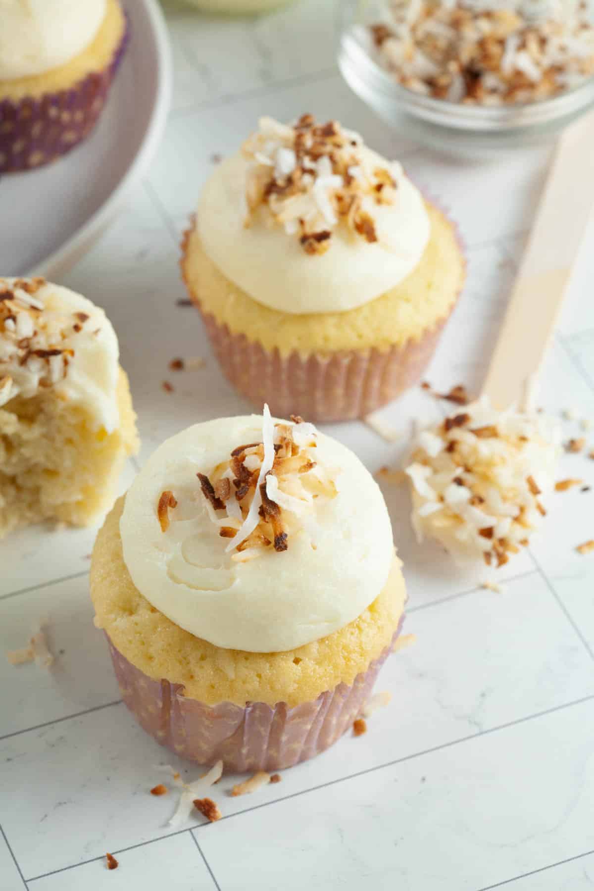 yellow cupcake with white frosting and toasted coconut on top