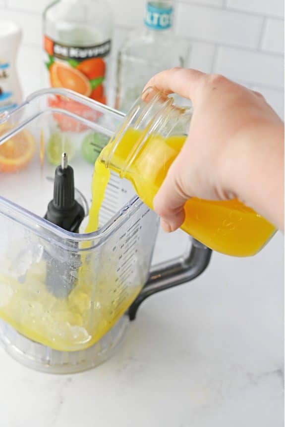 orange juice being poured into blender
