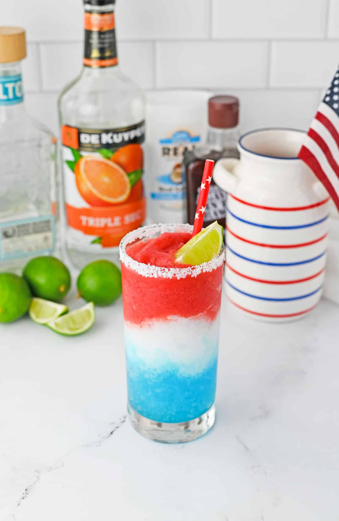 red white and blue slushy margarita in tall glass with lime wedge and red straw