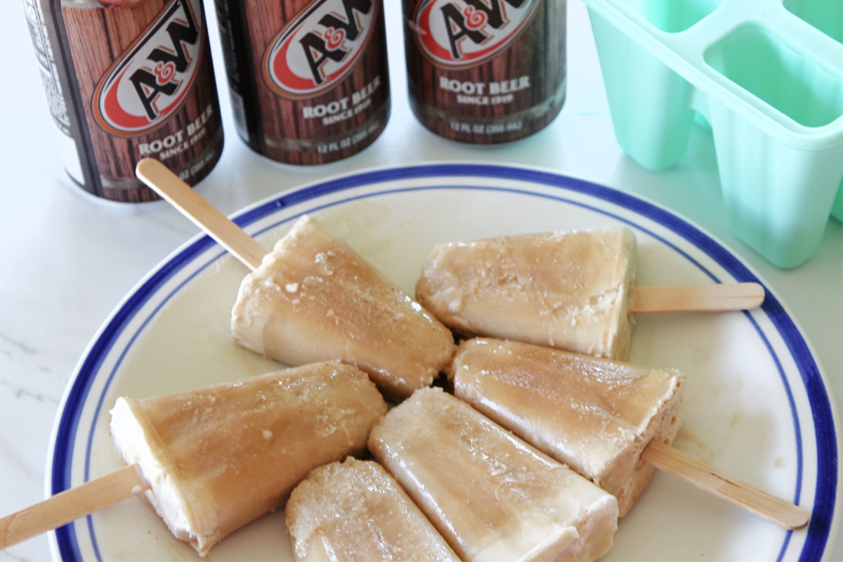 Root Beer Popsicles in a plate with beer on the side. 