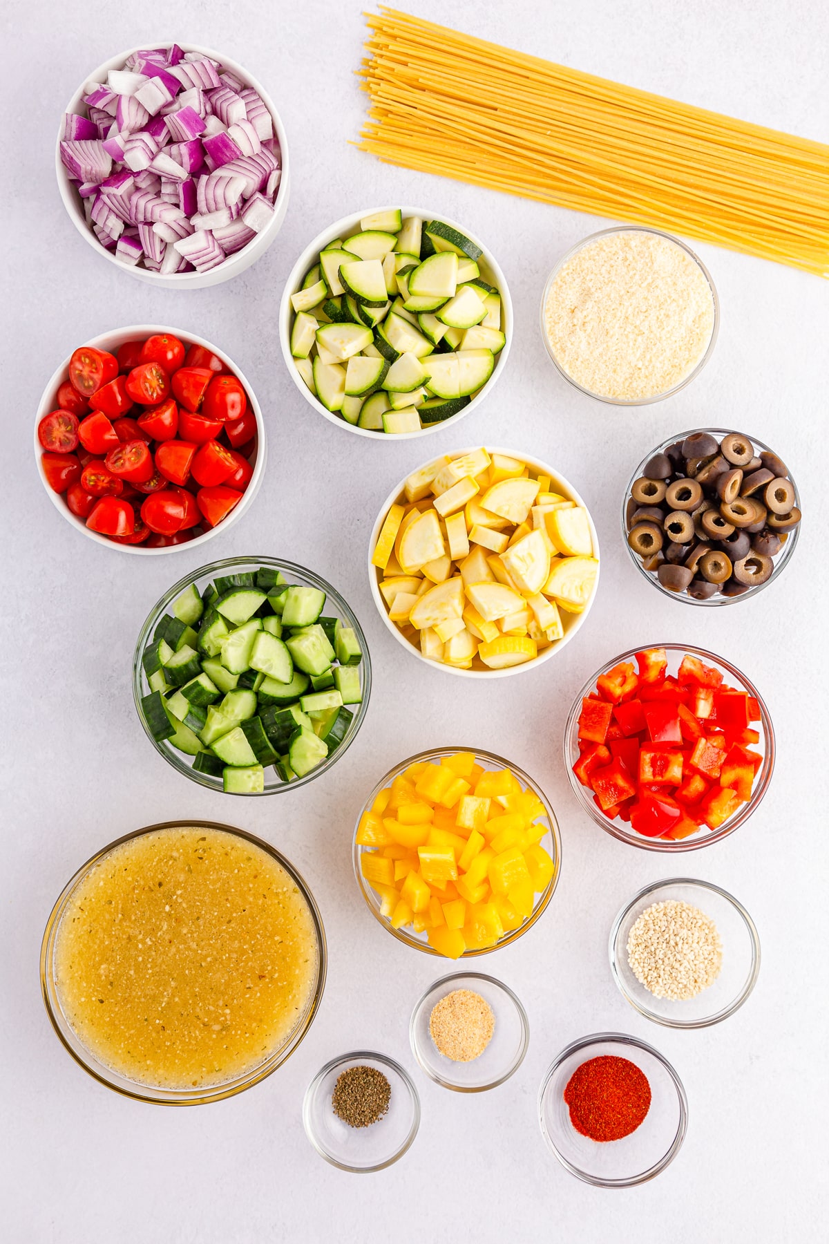 Ingredients for California Spaghetti Salad include spaghetti, cherry or grape tomatoes, English cucumber, red bell pepper, yellow bell pepper, red onion, black olives, yellow squash diced, and Zucchini. For the dressing, it include Italian salad dressing, grated parmesan cheese, sesame seeds, paprika, garlic powder, celery seeds