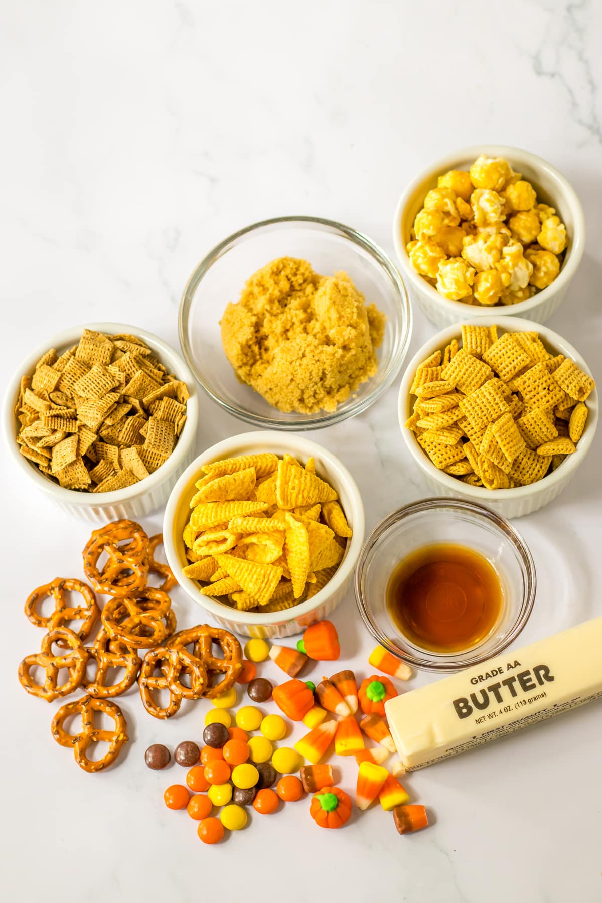 Ingredients for Fall Chex Mix Recipe include Unsalted butter, brown sugar, vanilla extract, wheat chex cereal, corn chex cereal, mini pretzel twists, bugles chips, reese's pieces candy, candy corn, candy corn pumpkins and caramel corn with peanuts (cracker jack)