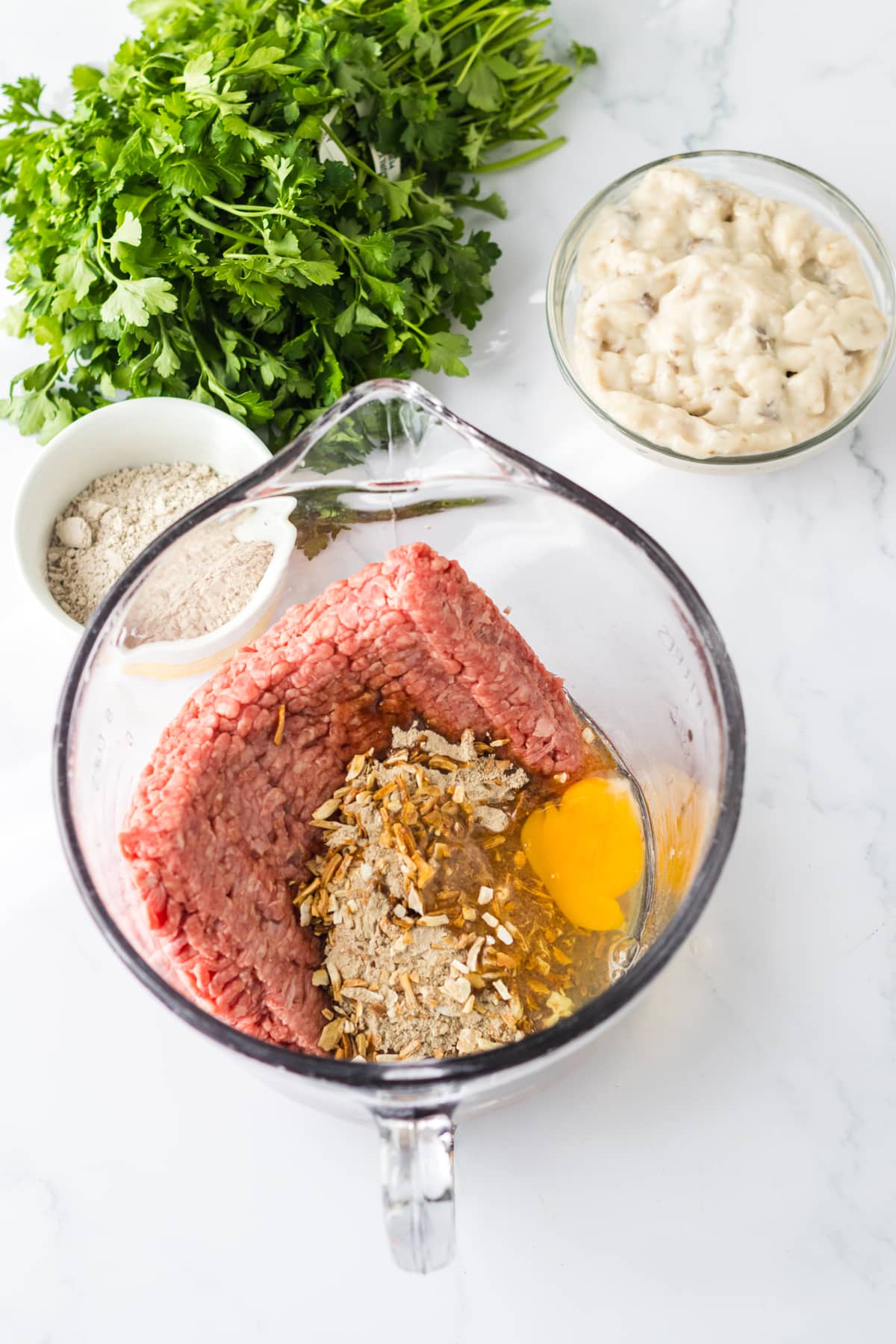 Part of making Slow Cooker Smothered Hamburgers is to prepare the patties. This process is done by combining ingredients such as ground beef, onion soup mix, egg, Worcestershire sauce, bread crumbs, and steak seasoning.