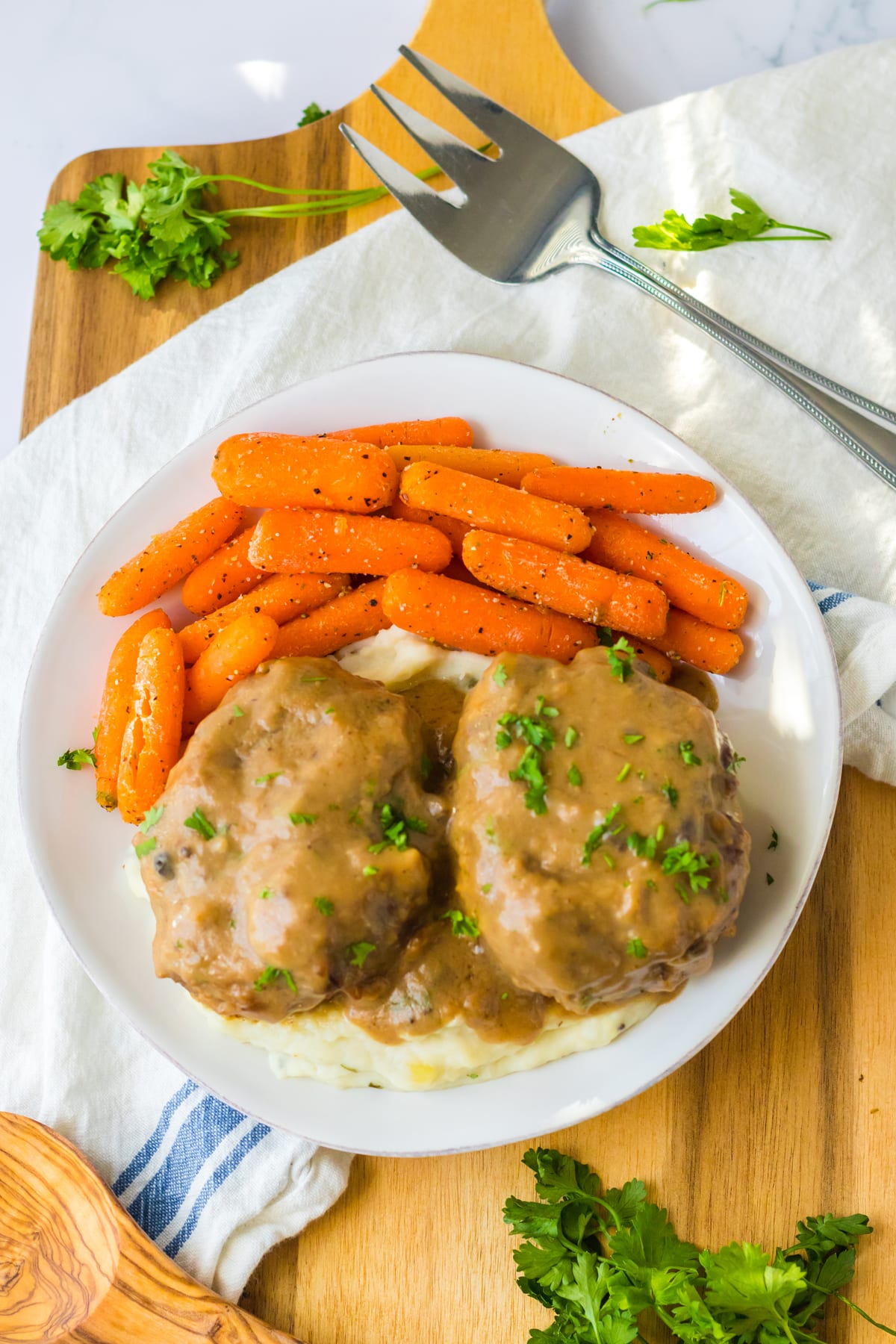 Slow Cooker Smothered Hamburgers with mashed potatoes and baby carrots.