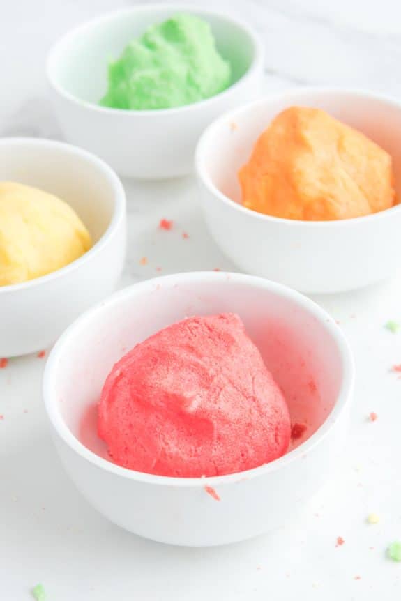 colored dough in four white bowls