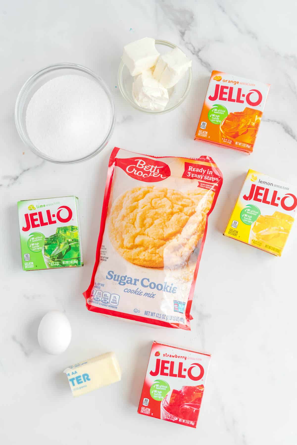 sugar cookie mix with boxes of jello, cubed cream cheese, 1 egg, half a stick of butter and sugar on counter