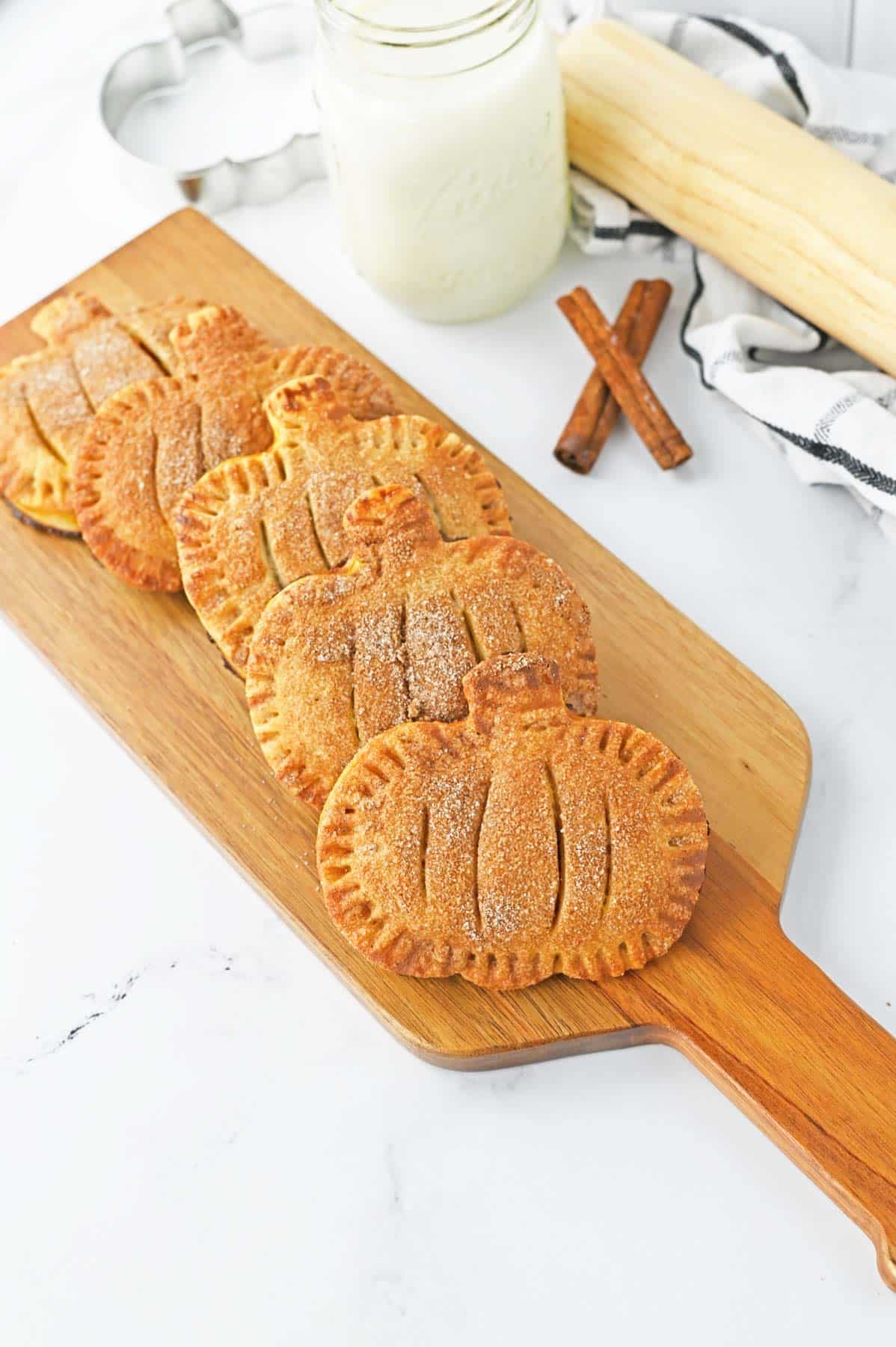 pumpkin hand pies on cutting board with glass of milk