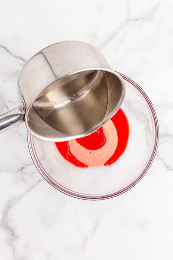 pouring hot water on jello mixture in glass bowl