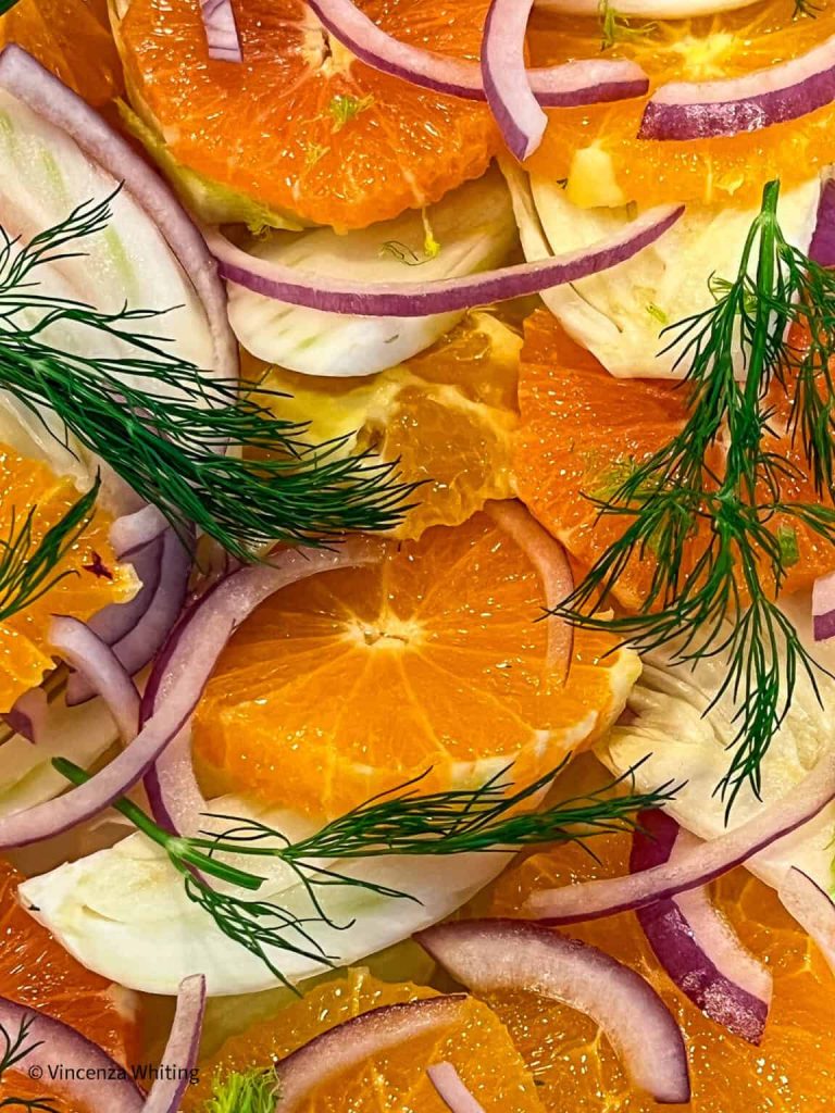 A close up of oranges, onions and dill.